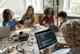 Kinder programmieren gemeinsam ein Videospiel am Computer.